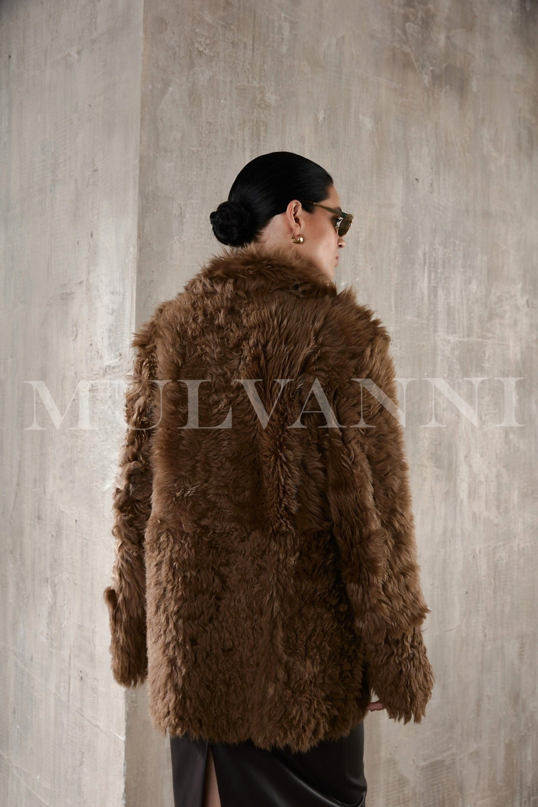 A stylish woman in a premium brown shearling coat, embodying both cozy comfort and elegant fashion with its thick, soft fabric and classic appeal.