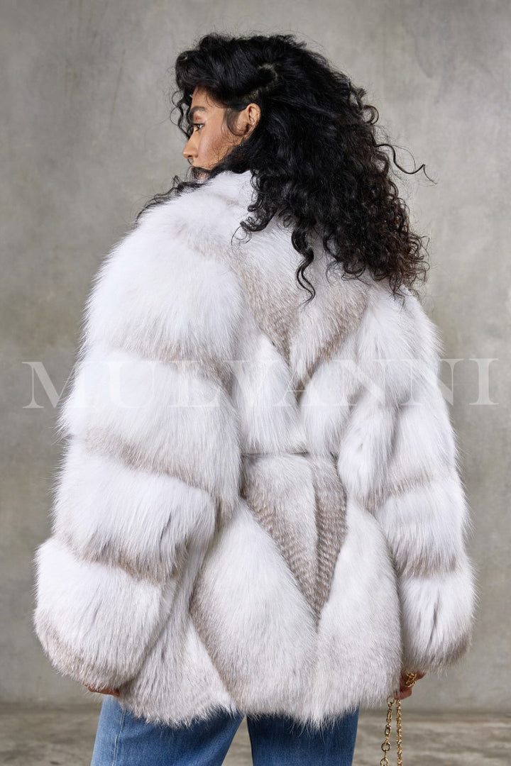 A woman models a very elegant crossed Arctic fox fur coat, meticulously crafted for volume and softness, featuring a hoodless cut that emphasizes its sophisticated and graceful silhouette.