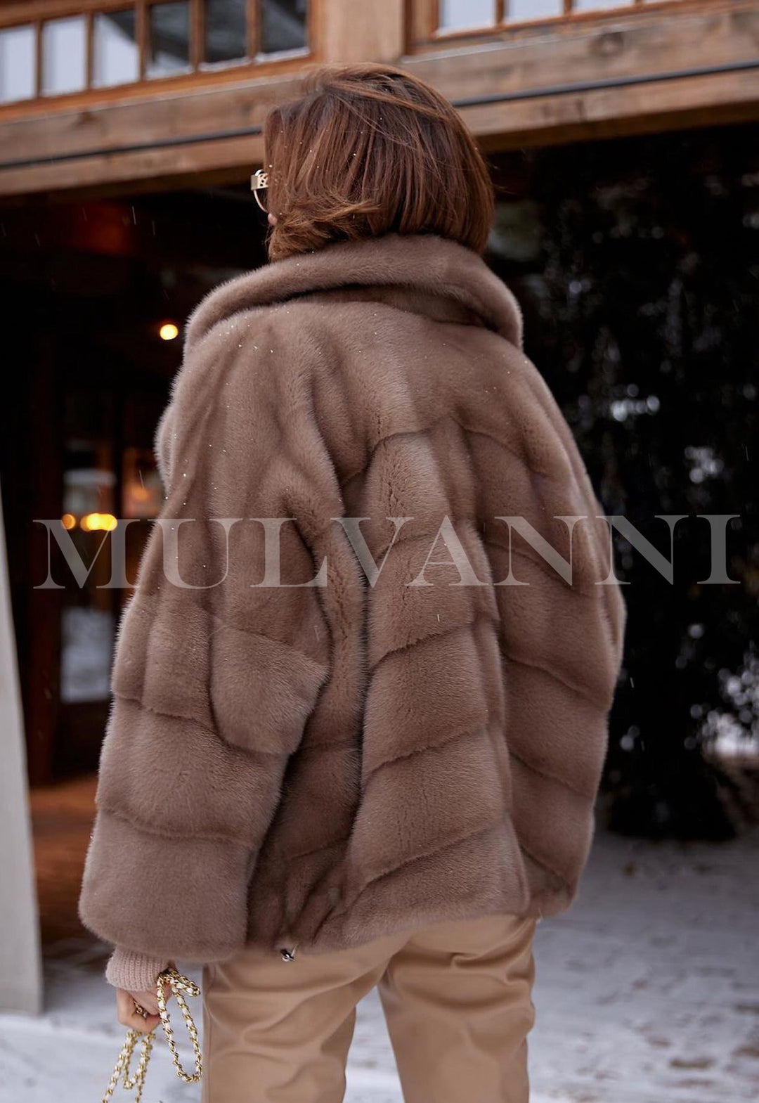 A woman in a luxurious short brown mink jacket, styled with fashionable sunglasses. The rich mink fur adds warmth and elegance, perfectly pairing with her chic accessories.