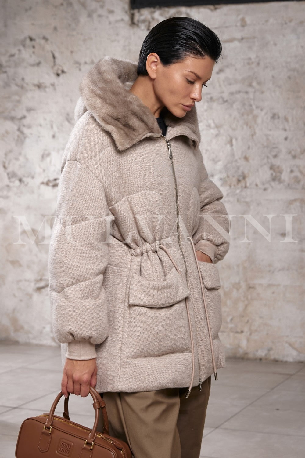 Woman walking outdoors in a fine wool puffer coat with mink fur hood, showcasing the jacket’s rich texture and reversible design.