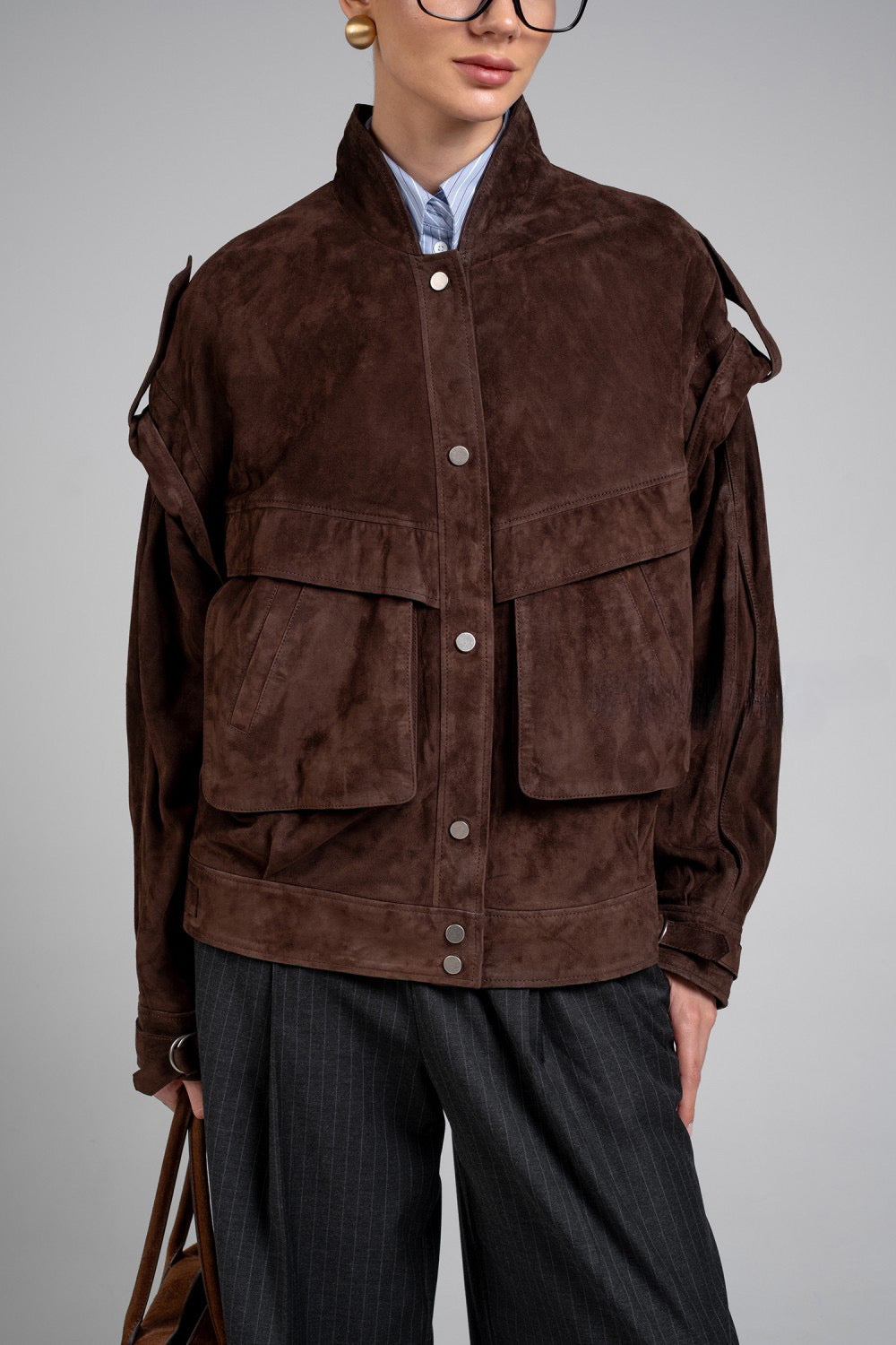 Wearing this dark brown suede jacket, the model highlights its timeless style and soft, supple texture.