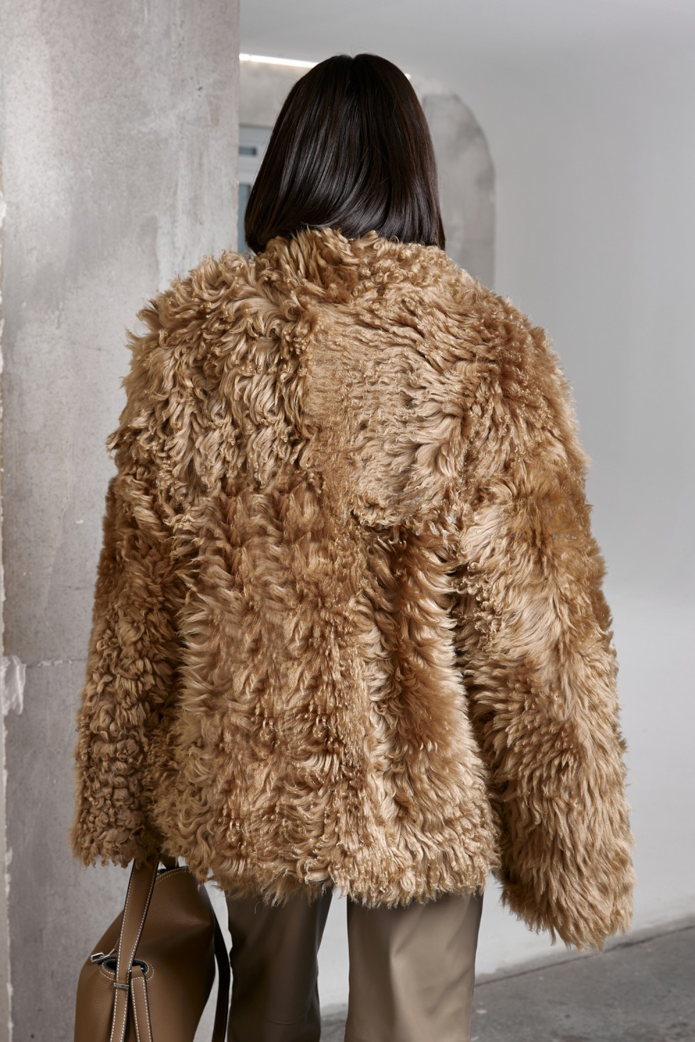 A woman showcases a plush ecru shearling coat with a relaxed silhouette, perfect for elevating winter looks.