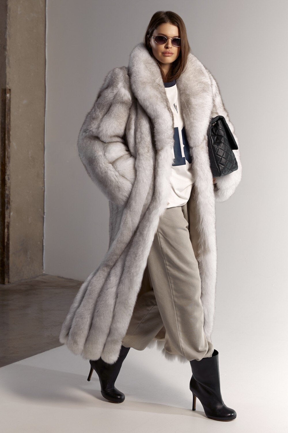 A woman dressed in a long white fox fur coat with elegant grey highlights, crafted from the finest natural fur for sophisticated winter style and Arctic-level protection.