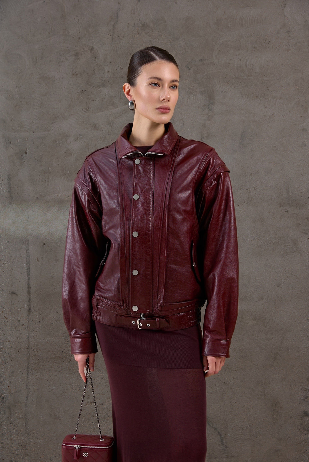 A woman wearing a versatile burgundy leather jacket crafted from supple genuine leather, featuring detachable sleeves for a stylish transition from jacket to vest.