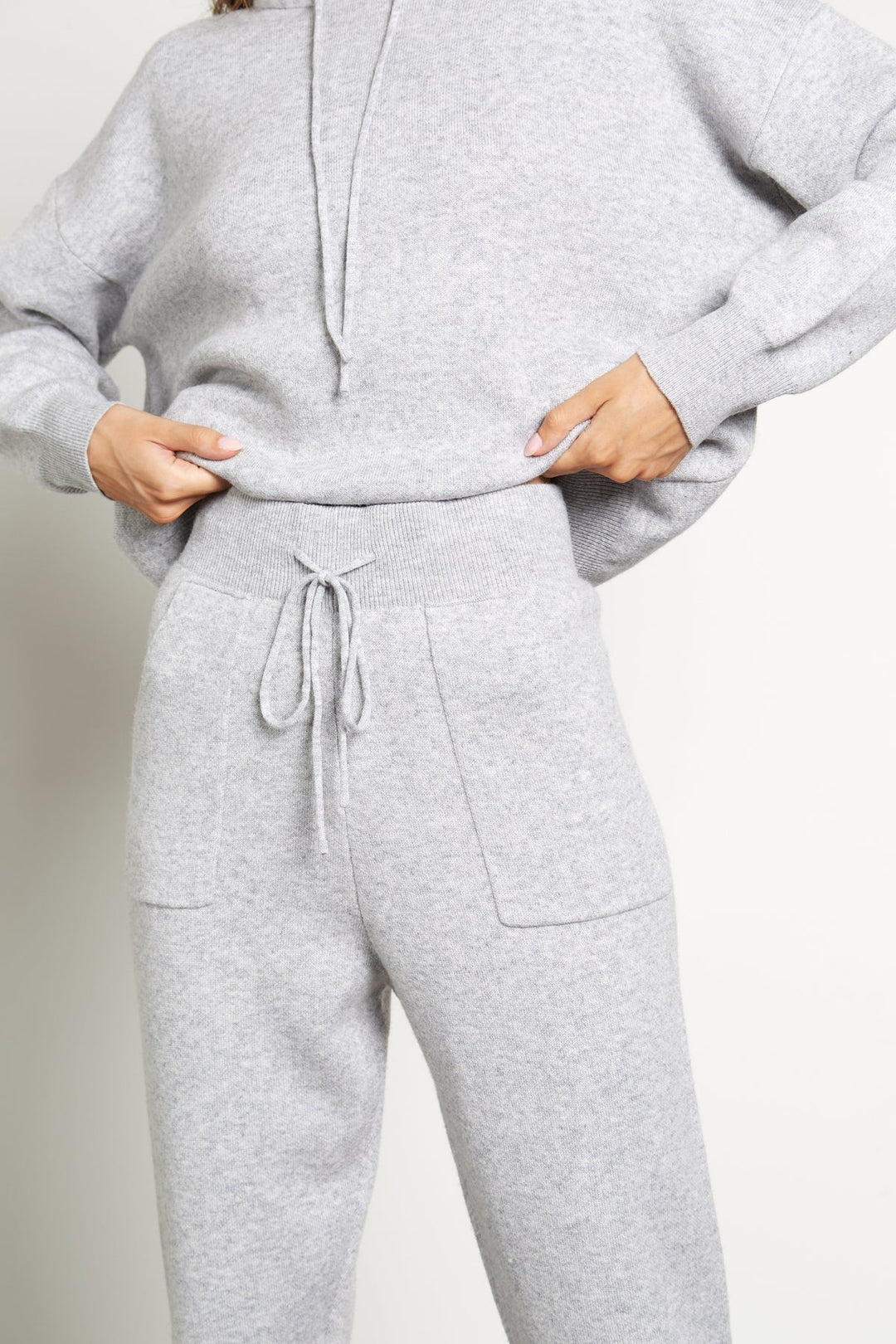 A woman wearing a grey wool cashmere tranksuit consisted of a sweater with fox fur trim and matching cashmere wool trousers.