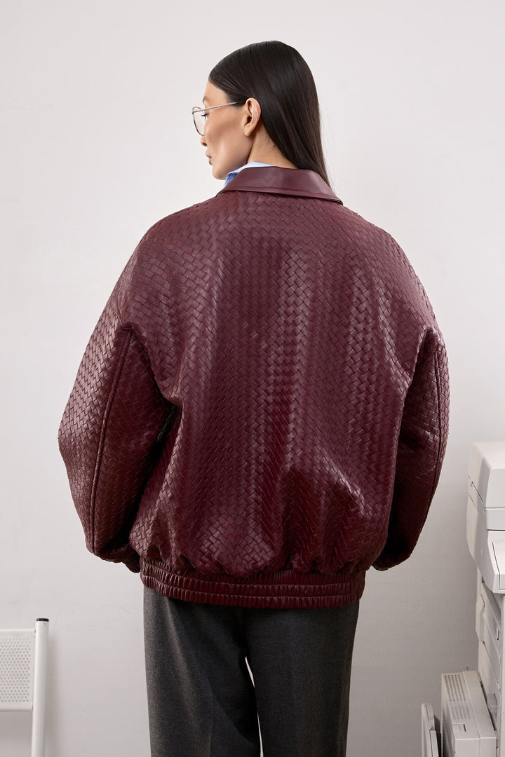 A woman in a burgundy bomber jacket featuring clean lines and side pockets, blending casual ease with contemporary sophistication.