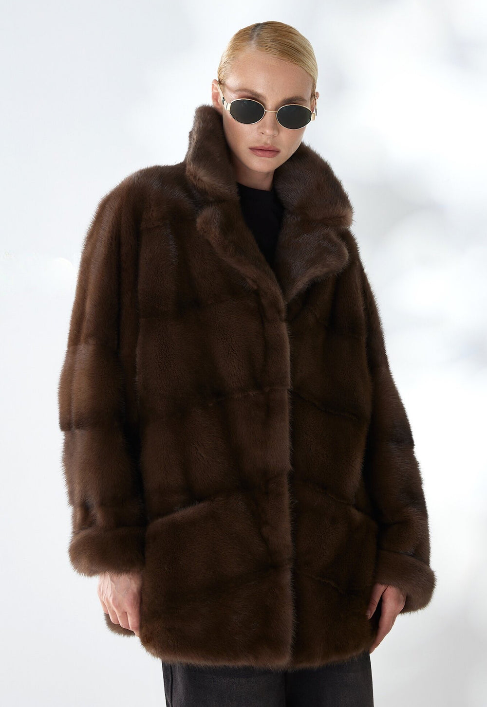 Elegantly dressed, a woman models a dark brown mink fur coat featuring a sleek silhouette and luxurious texture, perfect for elevating both day and evening looks.