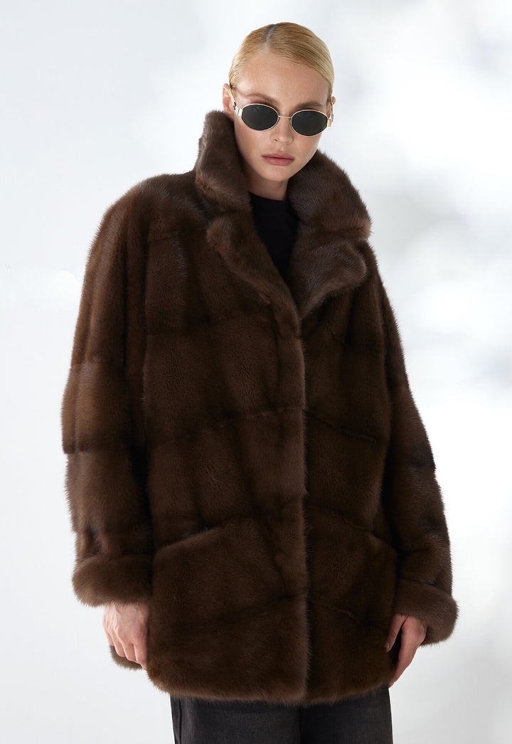Elegantly dressed, a woman models a dark brown mink fur coat featuring a sleek silhouette and luxurious texture, perfect for elevating both day and evening looks.