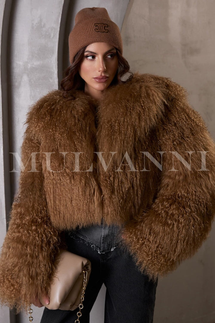 The brown short Mongolian fur coat enhances the woman's look, exuding elegance and sophistication with its plush fur and contemporary design.