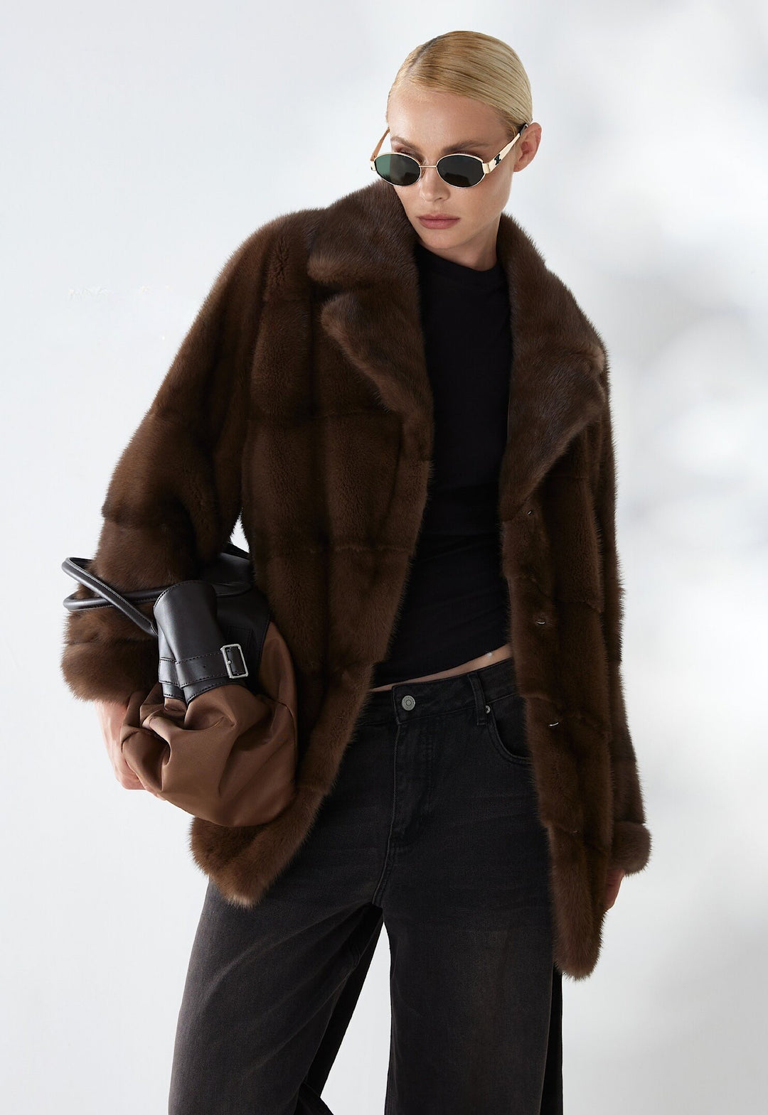 A woman wears a short dark brown mink fur coat, crafted from the finest genuine mink with a rich, velvety texture and natural sheen, exuding refined elegance and timeless luxury.