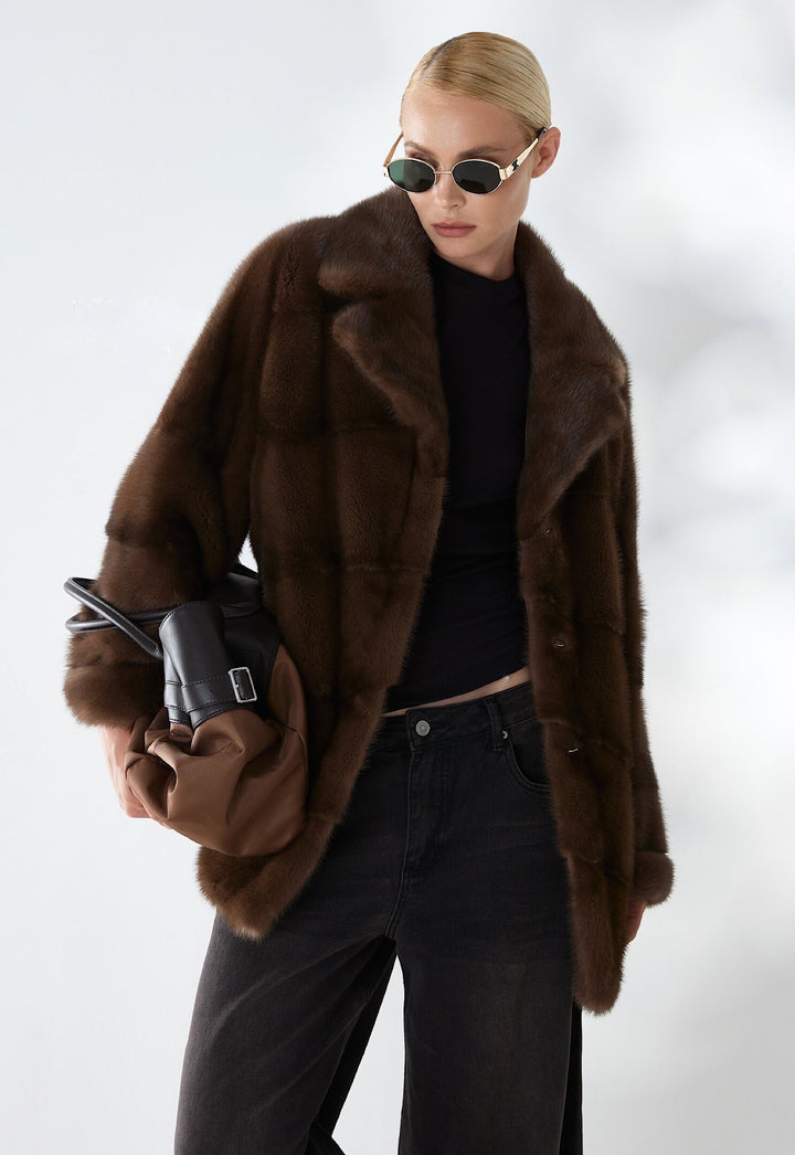 A woman wears a short dark brown mink fur coat, crafted from the finest genuine mink with a rich, velvety texture and natural sheen, exuding refined elegance and timeless luxury.