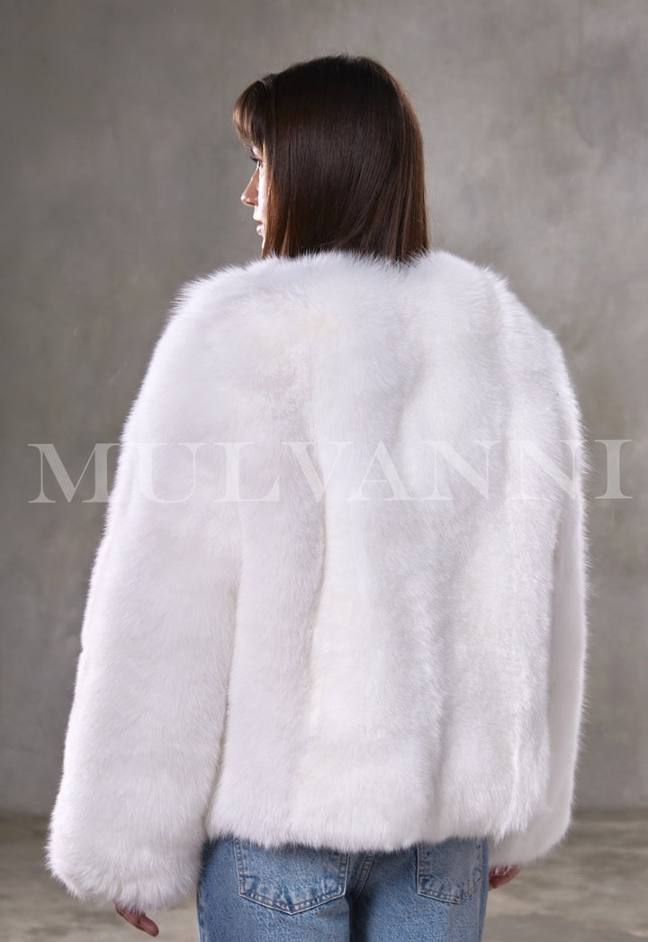 Woman showcases a thick, cropped genuine fox fur coat with long sleeves and subtle closures, pairing refined glamour with cozy warmth.