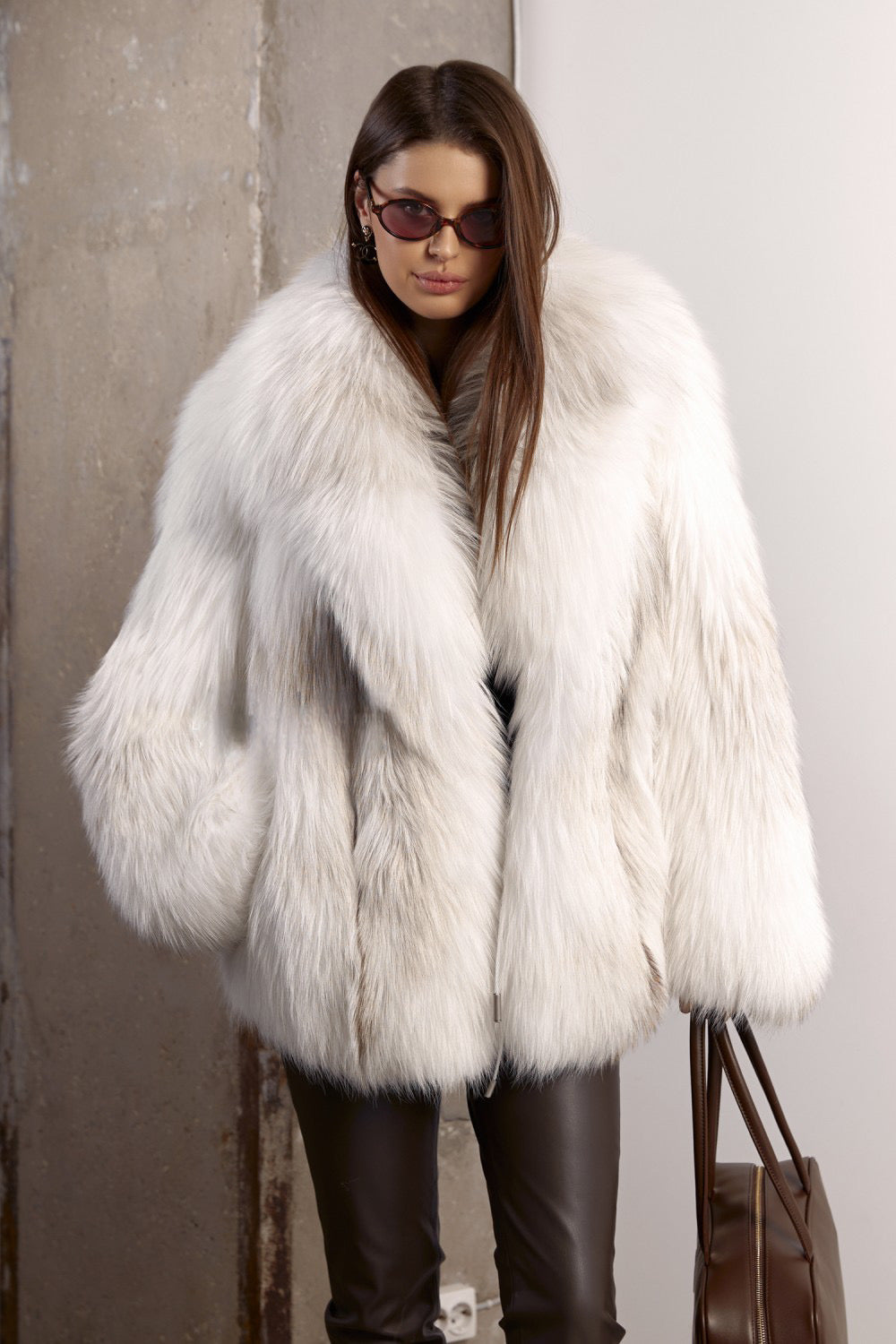A woman dressed in a luxurious Crossed White Fox Fur coat, showcasing its soft silvery hues, voluminous texture, and effortlessly chic silhouette.