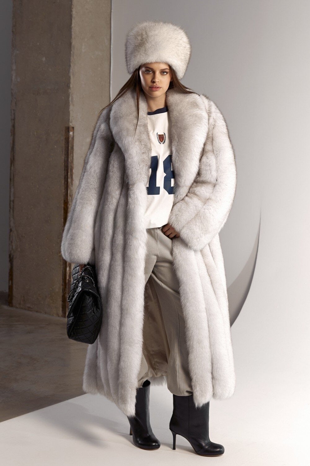 A woman models a natural white and grey fox fur coat designed for harsh winter conditions, paired elegantly with a traditional Slavic fox fur hat for full winter glamour.
