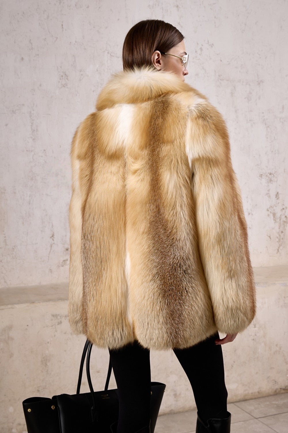 A woman models a show-stopping gold fox fur coat and sunglasses, tailored for both luxury and practicality in freezing weather, offering elite comfort and enduring style.