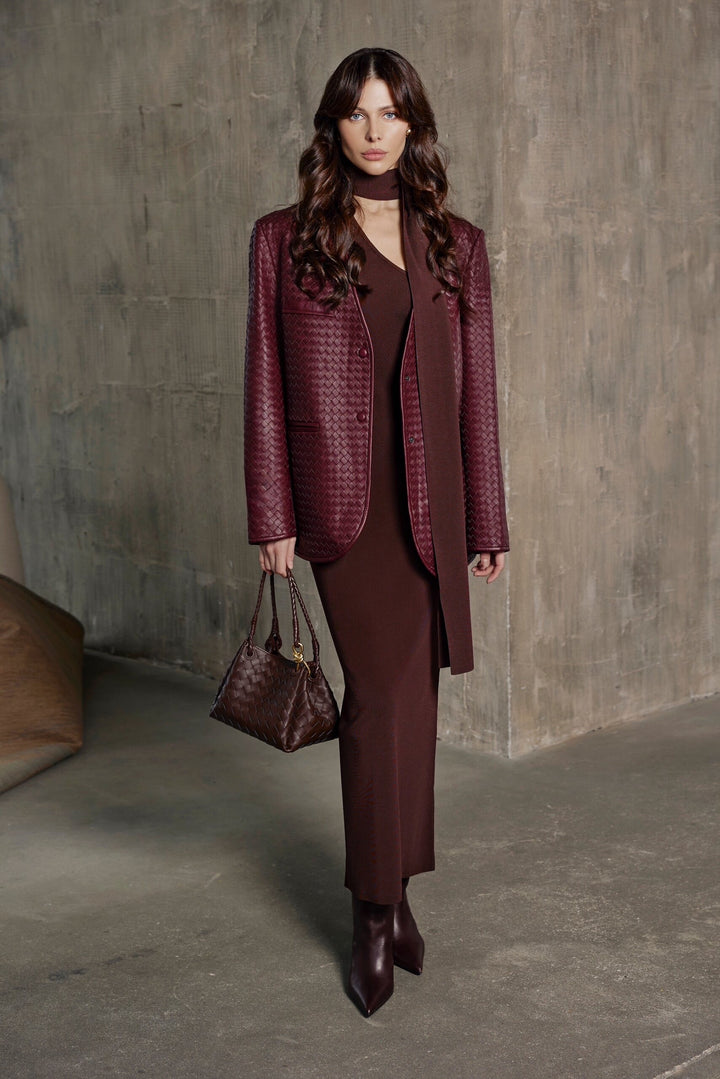 A woman dressed in a rich burgundy woven blazer with a perfectly tailored silhouette, showcasing elegance and contemporary chic.