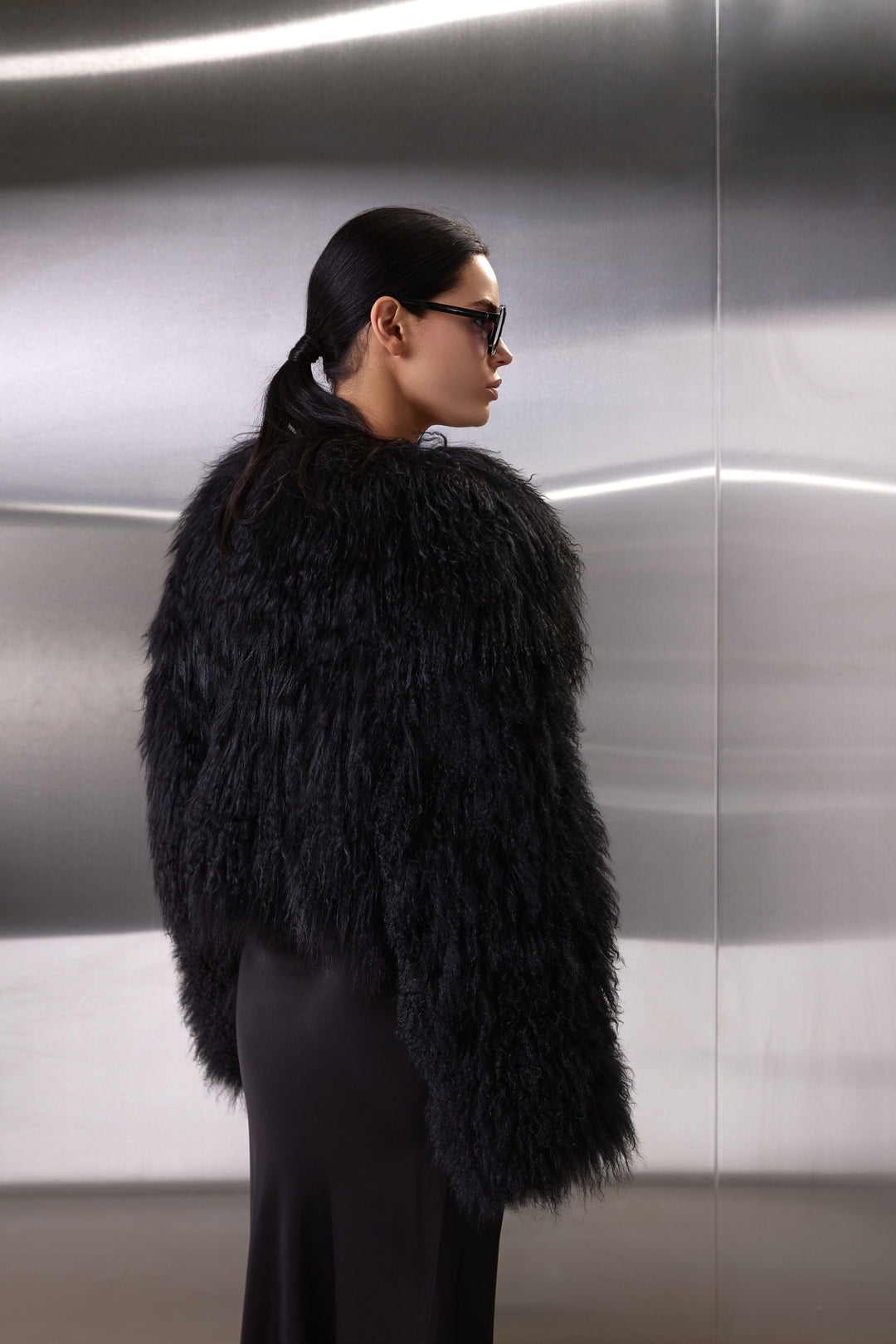 A woman dons the genuine Mongolian Coat, blending plush fur warmth with chic hidden snaps and side pockets for a polished winter look.