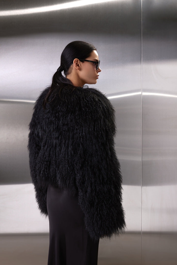 A woman dons the genuine Mongolian Coat, blending plush fur warmth with chic hidden snaps and side pockets for a polished winter look.