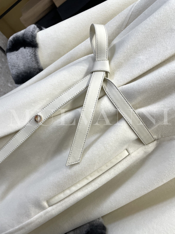 Close-up of a women’s cashmere cape with rex rabbit fur trim and leather belt, showcasing high-quality fabrics and classic design.