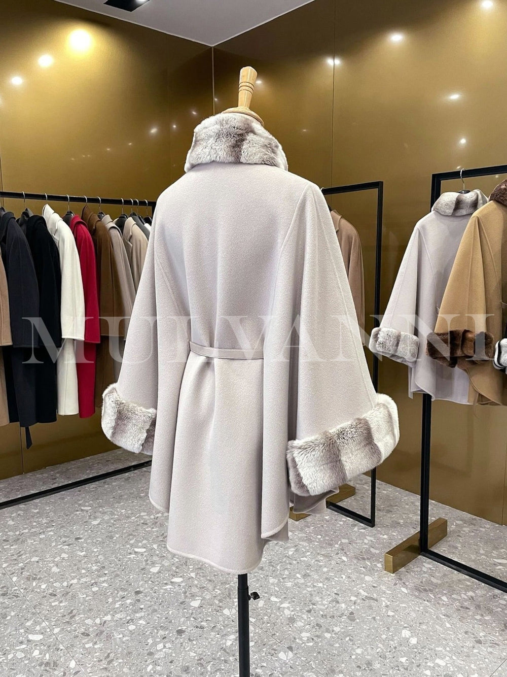 Elegant women’s cashmere cape with rex rabbit fur, showcasing high-quality fabrics in a luxurious fashion boutique.