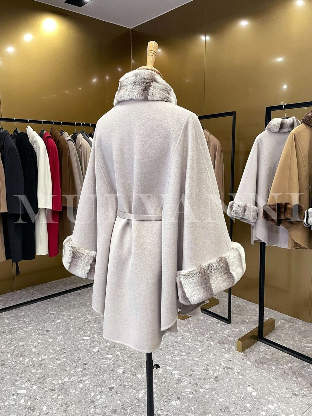 Elegant women’s cashmere cape with rex rabbit fur, showcasing high-quality fabrics in a luxurious fashion boutique.
