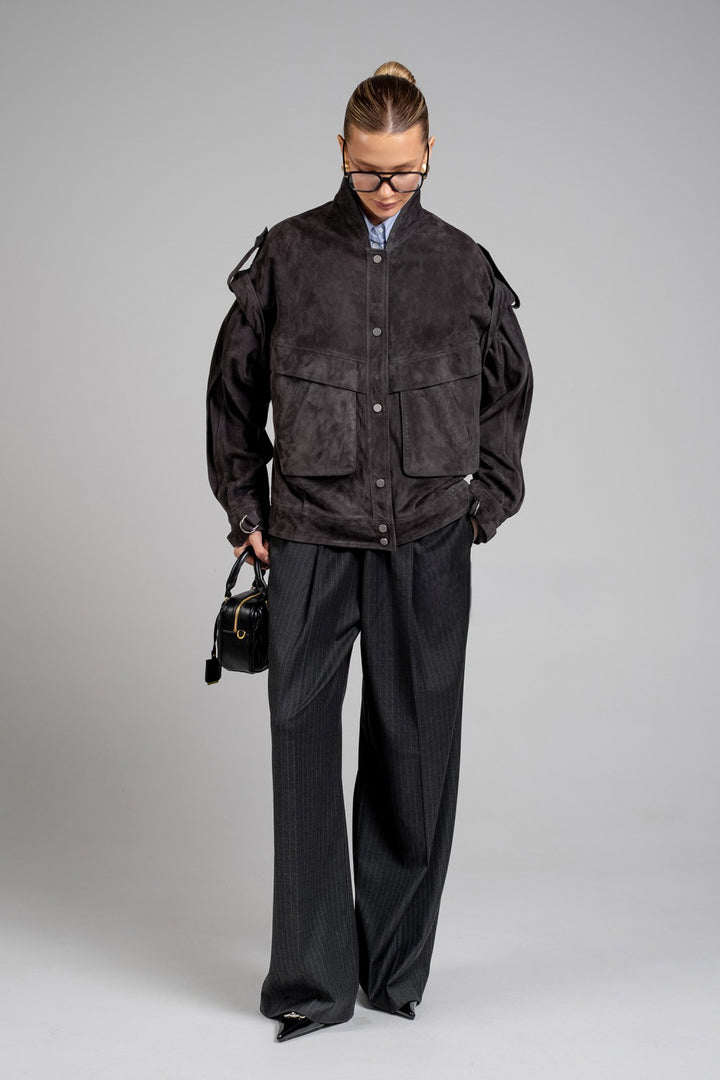 Stylishly dressed, a woman models a charcoal suede jacket that blends trendy design with everyday practicality and timeless appeal.