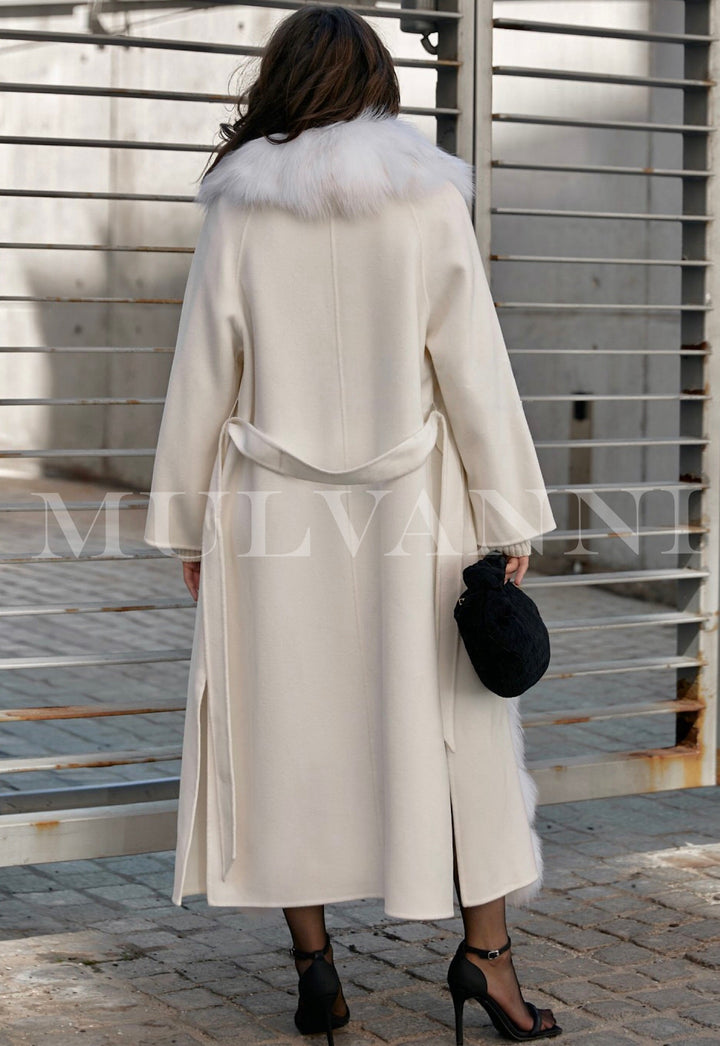 A woman elegantly models a white cashmere coat adorned with fluffy white fox fur, combining classic style with sumptuous winter comfort.