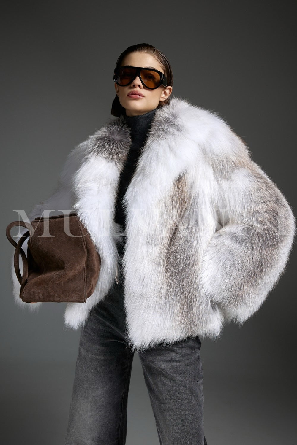 Styled in a full-length crossed fox fur coat, the woman adds a soft contrast with a brown suede bag, creating a sophisticated and timeless ensemble.