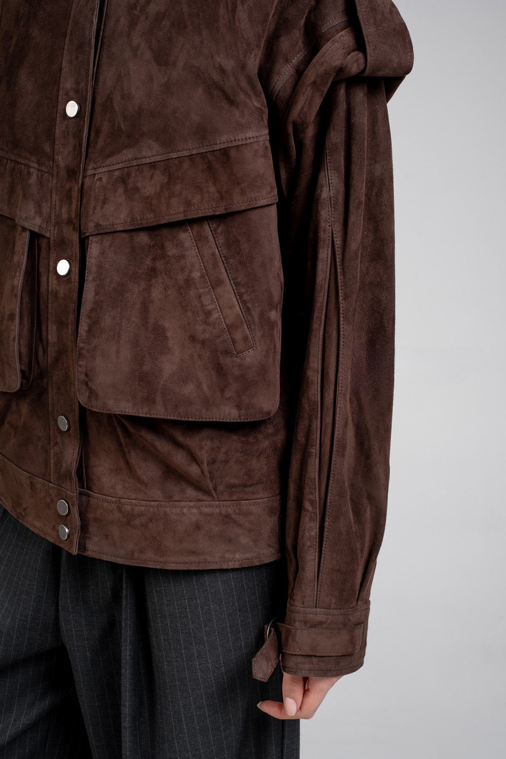 A model styled in a versatile dark brown suede leather jacket, blending comfort and chic fashion effortlessly.