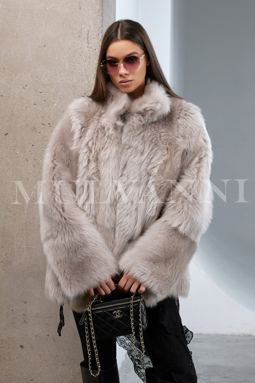 Woman gracefully wearing a premium shearling coat, showcasing its thick, plush texture and refined silhouette in a winter setting.