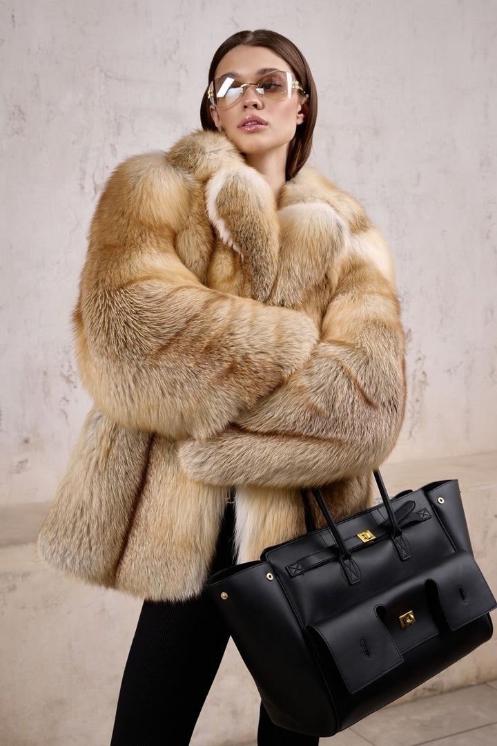 A woman in a full pelt gold fox fur coat designed for Arctic climates, showcasing exceptional craftsmanship and warmth, paired effortlessly with oversized sunglasses.