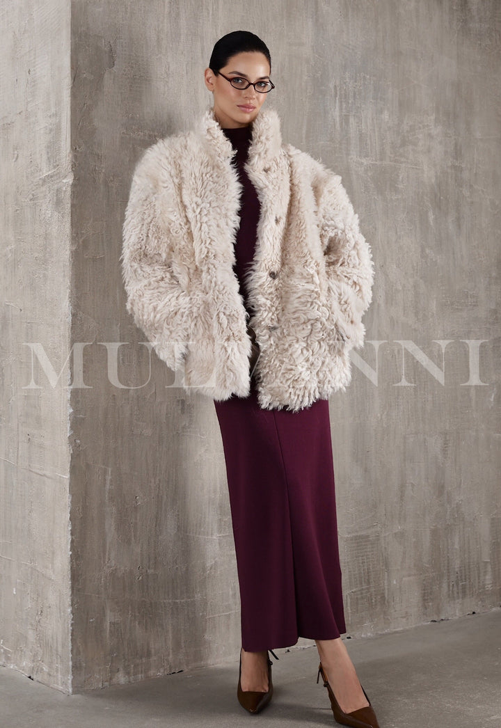 A cropped beige shearling coat for women, offering a snug, comfortable feel with its soft inner lining. The coat includes oversized lapels and a sleek design, perfect for layering during colder weather.