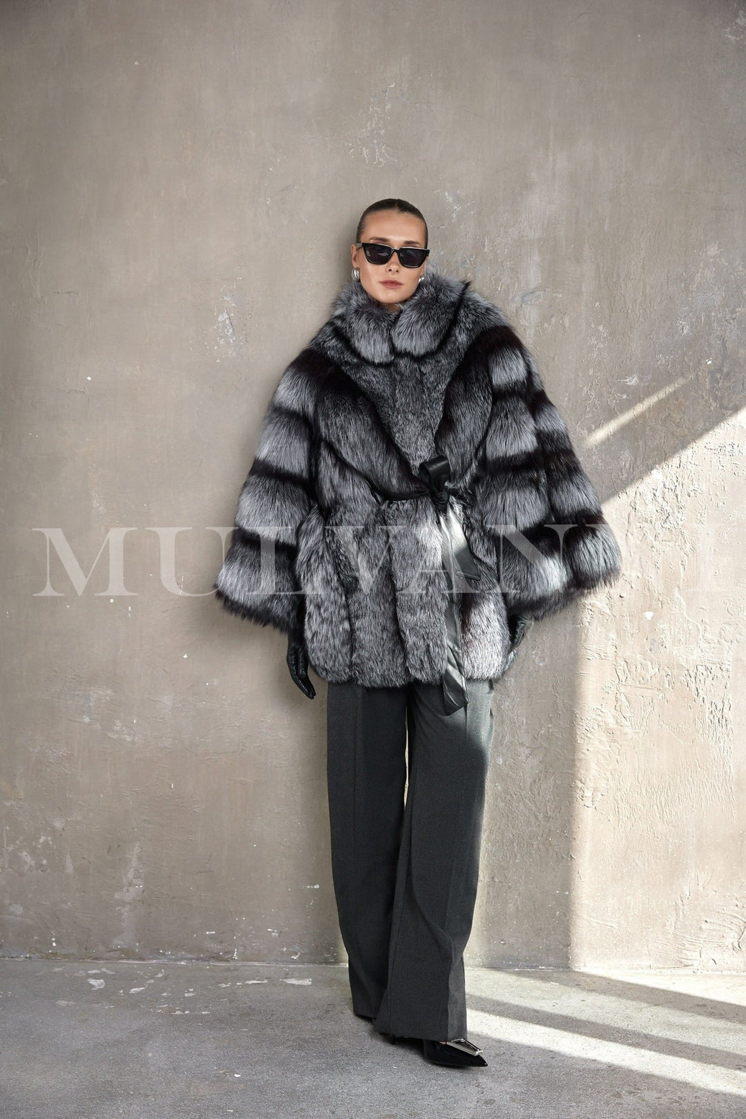 Model dressed in a luxurious silver fox fur coat, featuring oversized proportions and a sleek leather belt for timeless sophistication.