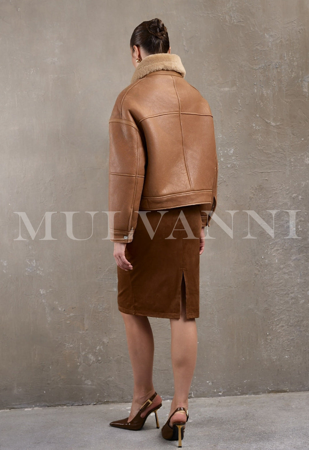 Wearing an oversized brown shearling bomber, the woman displays a sporty yet feminine winter look with silver hardware details.