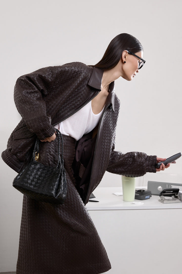 A woman dressed in a rich brown bomber jacket with a softly structured shape and side pockets, adding a stylish and versatile layer to her outfit.