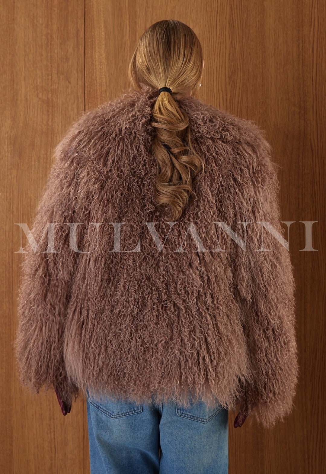 Wrapped in thick brown Mongolian fur, the woman wears a glamorous long coat with a high collar and satin-leather interior finish.