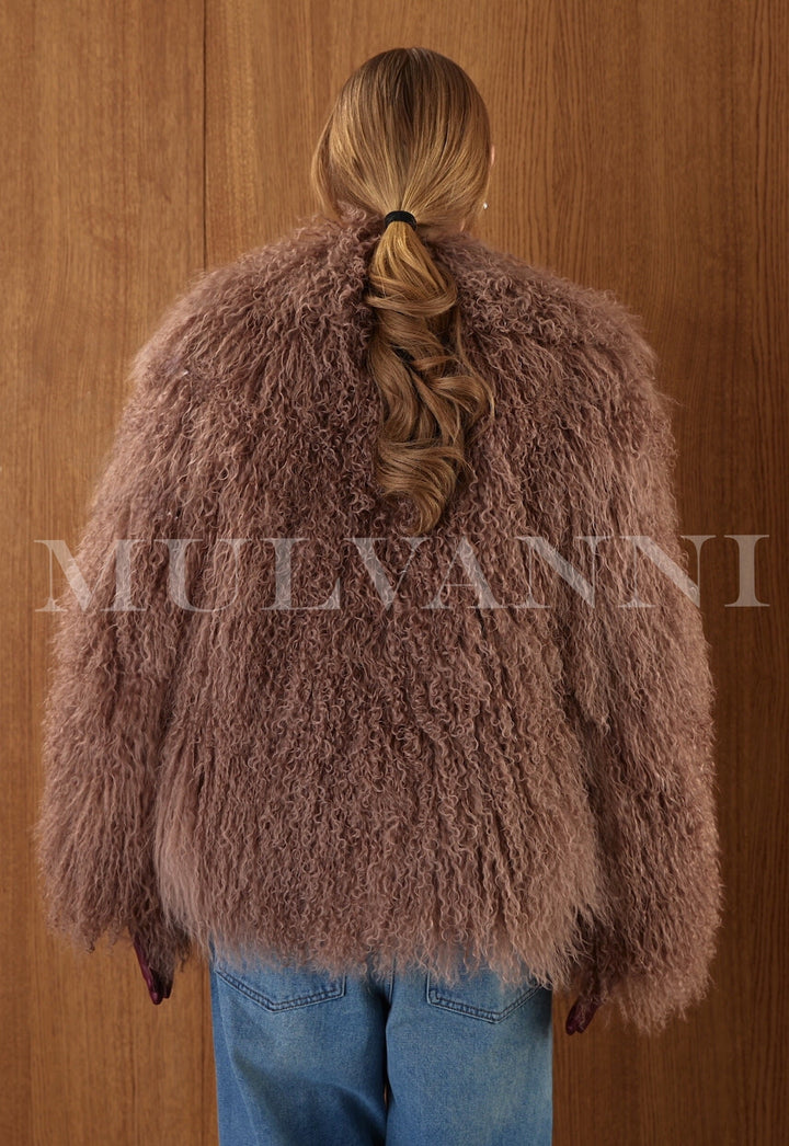 Wrapped in thick brown Mongolian fur, the woman wears a glamorous long coat with a high collar and satin-leather interior finish.