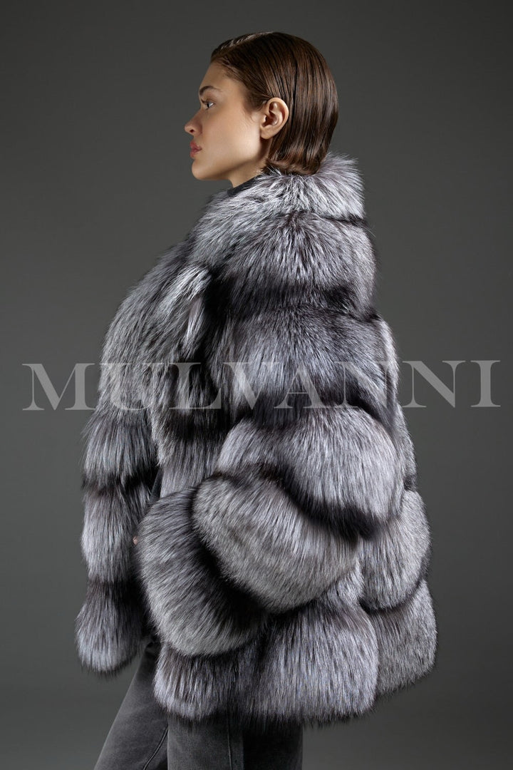 Woman steps out in a plush Silver Fox Fur Coat, carrying a minimalist black leather bag—an effortlessly trendy combination of warmth and modern sophistication.