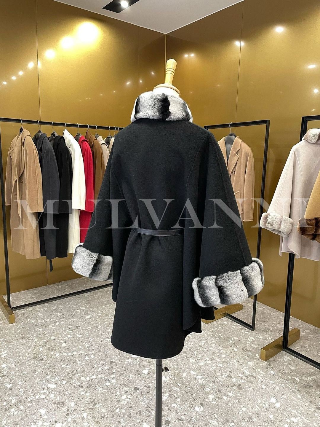 Elegant women’s black cashmere cape with luxury rex rabbit fur trim, featuring a structured funnel neckline and leather belt, displayed in a boutique.