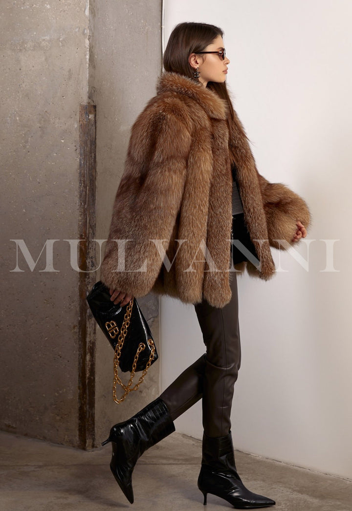 Dressed in a radiant natural fox fur coat, the woman pairs it with fitted brown leggings and a structured black leather bag for a chic, refined look.