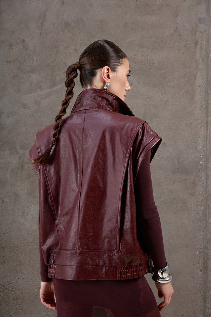 A woman wearing a detachable-sleeve burgundy leather jacket, styled head-to-toe in matching burgundy for a sleek and unified fashion statement.