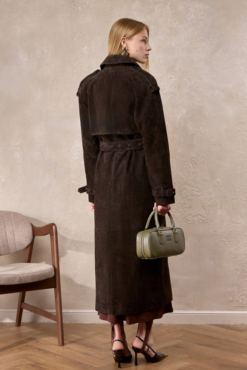 A woman dons the Hatti suede leather trench coat, highlighting the luxurious material and sleek, structured design ideal for layering.