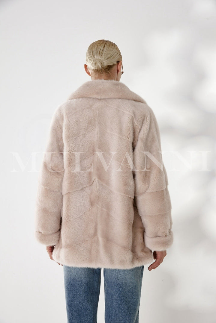 Elegantly worn by a woman, this artisan-crafted mink coat combines luxurious mink fur and satin lining for a polished, glamorous winter look.