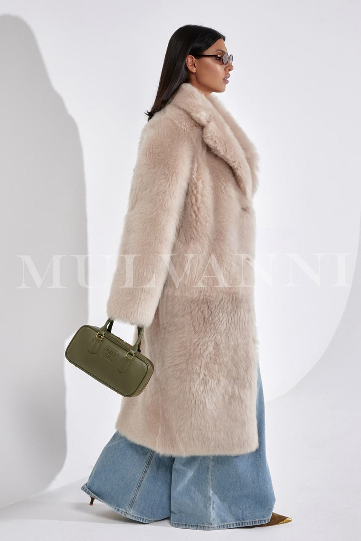 Wrapped in a rich shearling coat, the woman showcases cold-weather sophistication with the coat’s longline cut and premium finish.