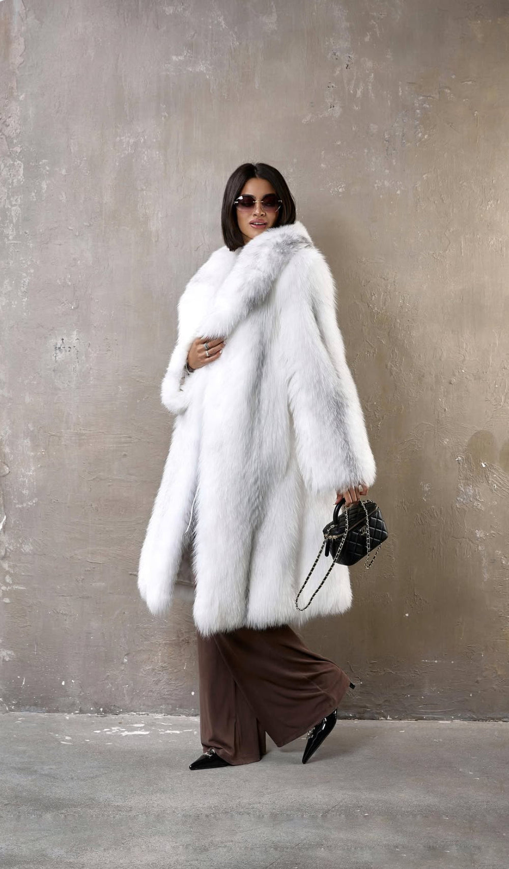 Styled in timeless elegance, a woman wears a luxurious crossed fox fur coat with dense, silken fur in natural muted shades—perfect for harsh winter climates.