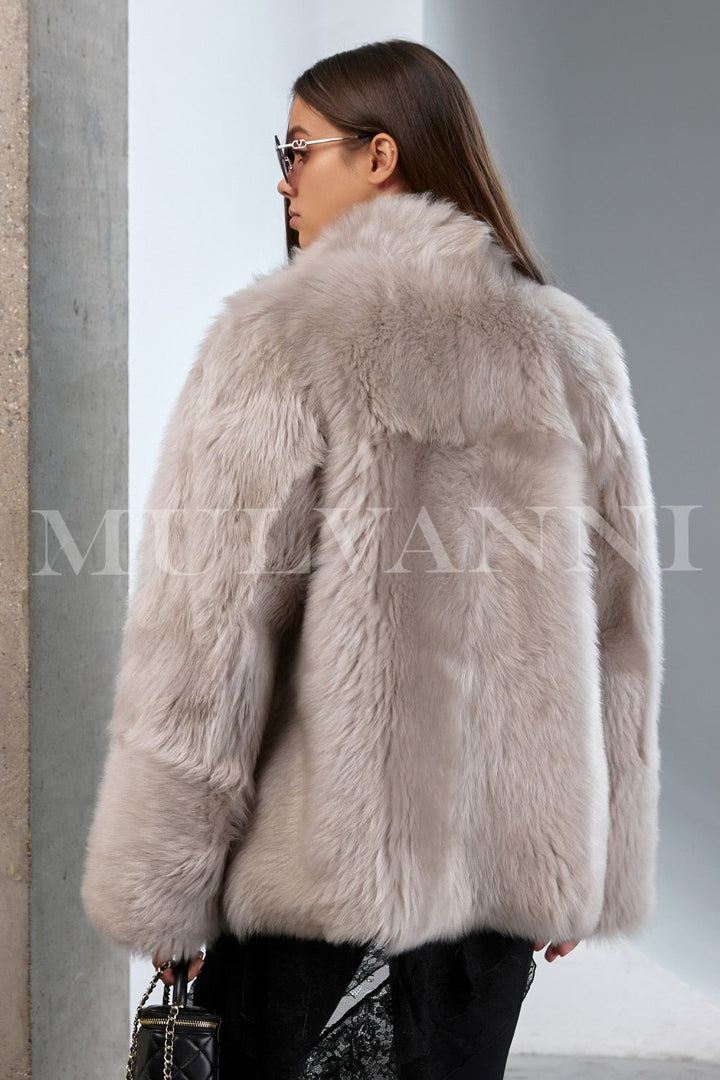 Effortlessly chic outfit featuring a soft shearling coat draped on a woman, combining heritage design with modern elegance.