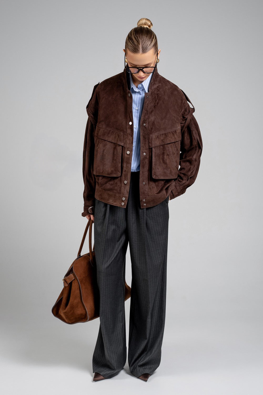 A model wears this dark brown suede jacket, combining trendy style with everyday practicality in a soft, high-quality leather design.