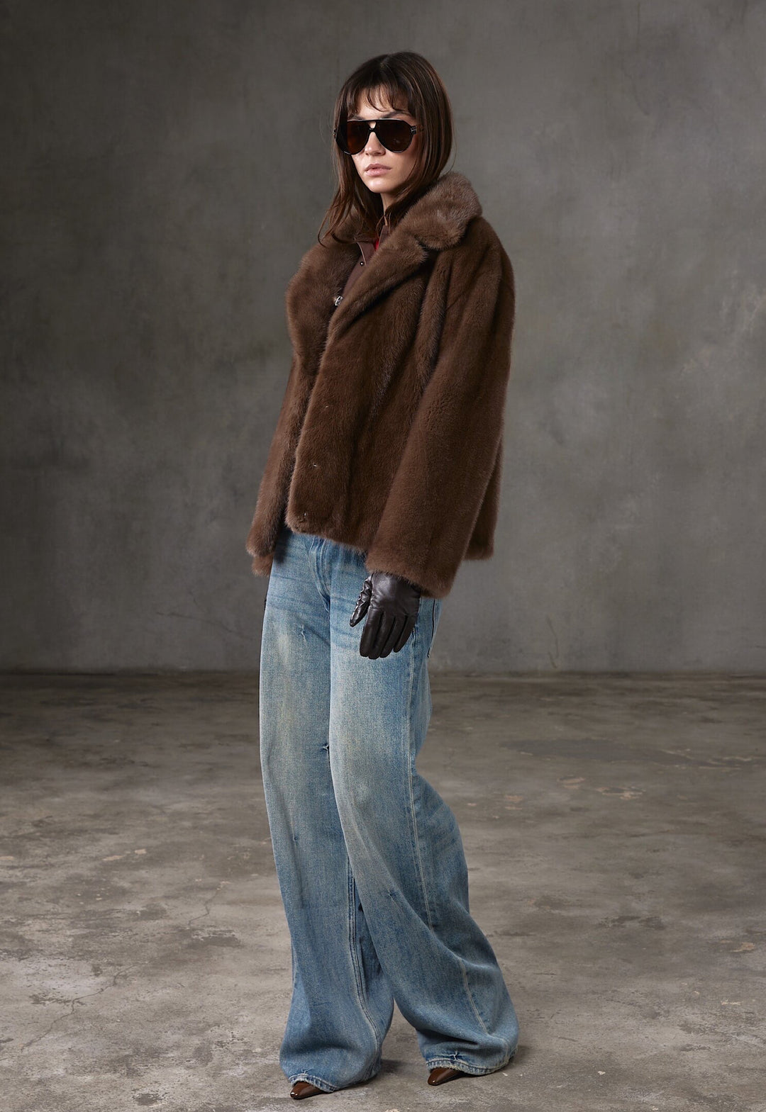 A woman dressed in a refined brown mink fur coat with a sleek silhouette, wearing trendy sunglasses to elevate her day-to-evening outfit.