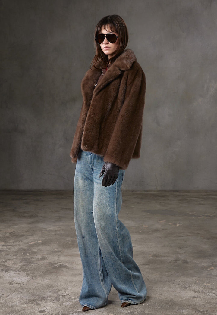 A woman dressed in a refined brown mink fur coat with a sleek silhouette, wearing trendy sunglasses to elevate her day-to-evening outfit.