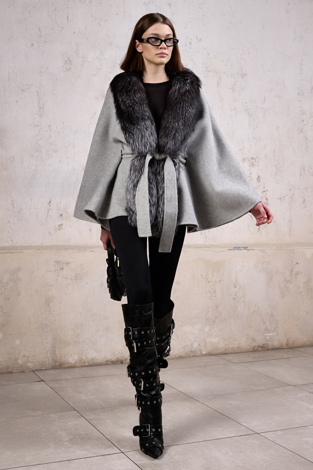 Elegantly dressed, a woman models a cashmere cape with luxurious silver fox fur, perfect for adding warmth and sophistication to any look.